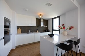 Een moderne keuken met witte kastjes, een centraal eiland met een zwarte kom, en een raam met uitzicht.