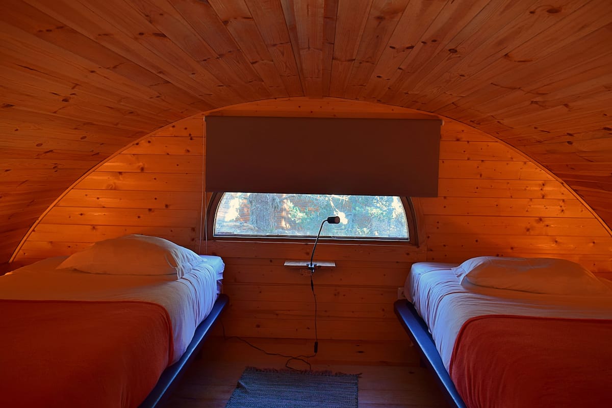 A cozy room with two beds, a window, and a ceiling fan.