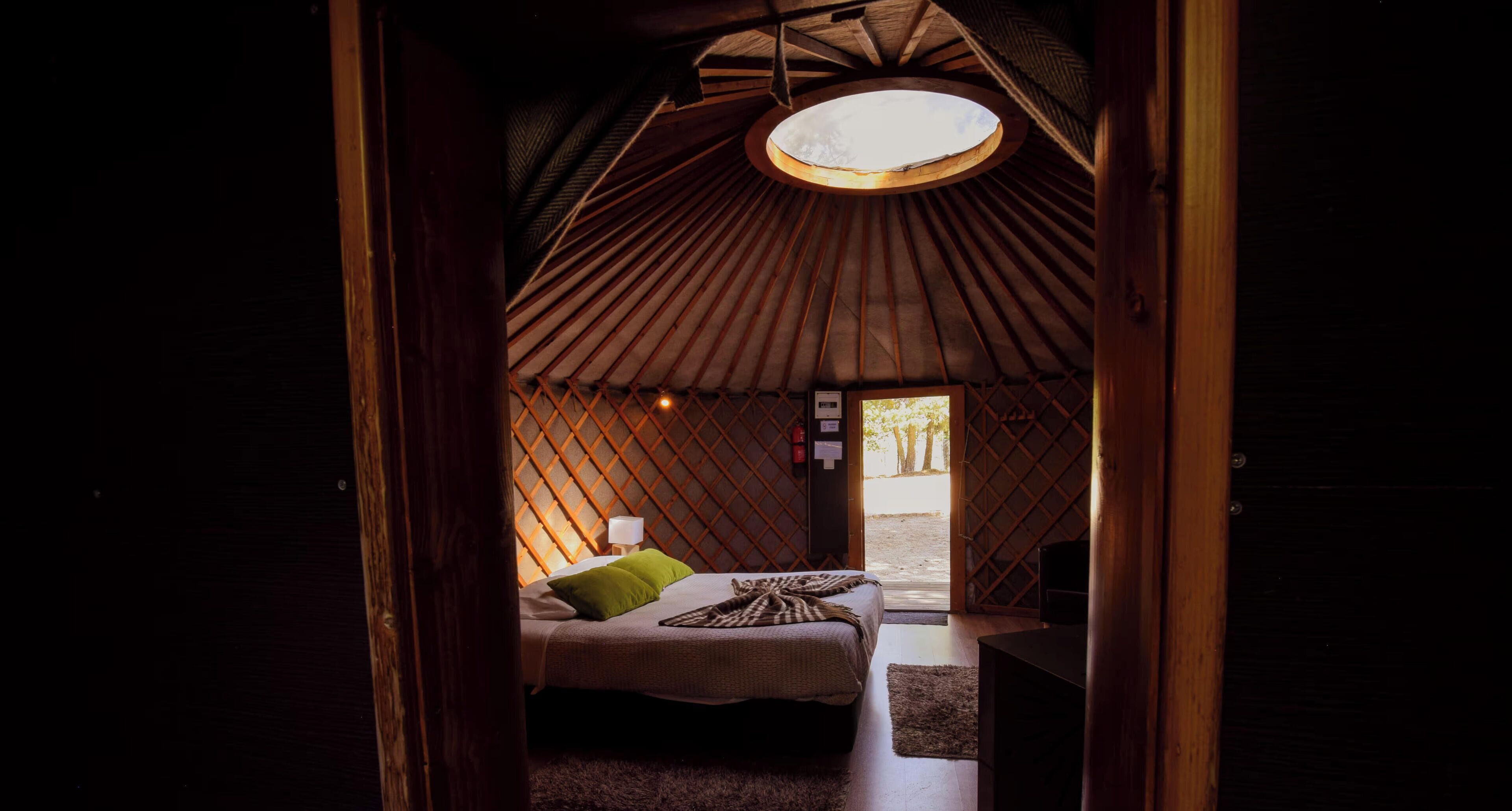 A cozy room with a bed, a small table, and a circular skylight.