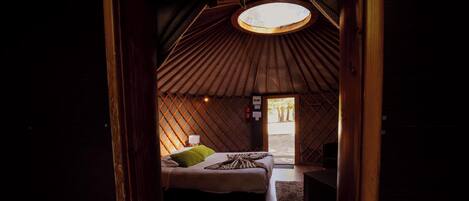 A cozy room with a bed, a small table, and a circular skylight.