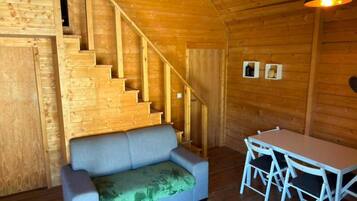 A wooden interior with a sofa, a dining table, and a staircase.