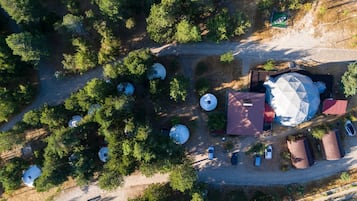 Vue aérienne d’un terrain de camping avec des tentes, une grande structure en forme de dôme et plusieurs réservoirs sphériques.