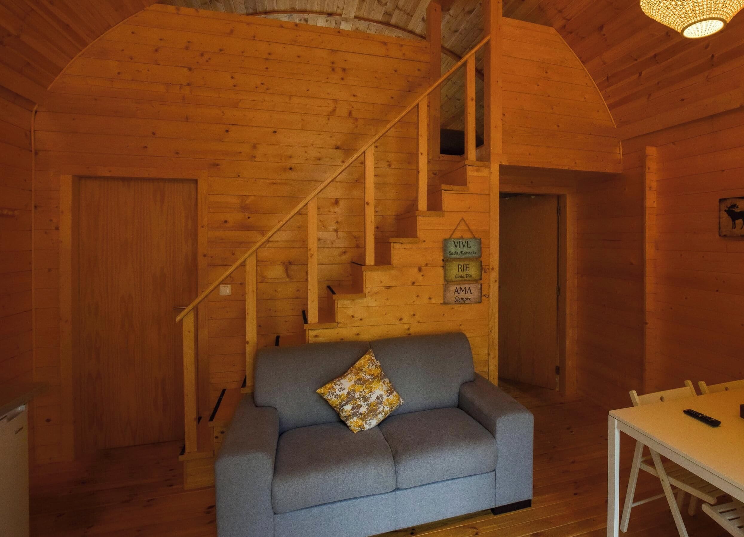 Un interior de madera con un sofá, una escalera y una mesa.
