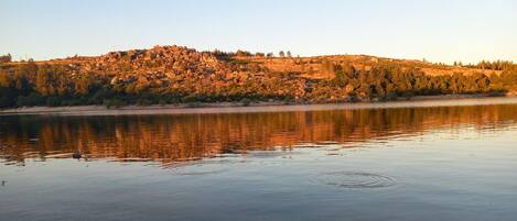 A calm lake with a rocky hill in the background.