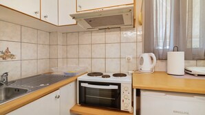 A compact kitchen with a stove, oven, and a kettle on the counter.