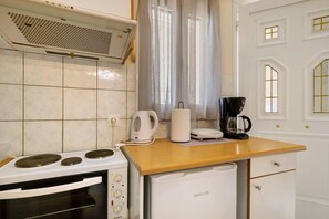 A compact kitchen with a stove, a coffee maker, and a refrigerator.