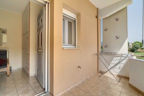 Un balcón con un tendedero, una ventana y una puerta que da a una habitación con cama y armario.