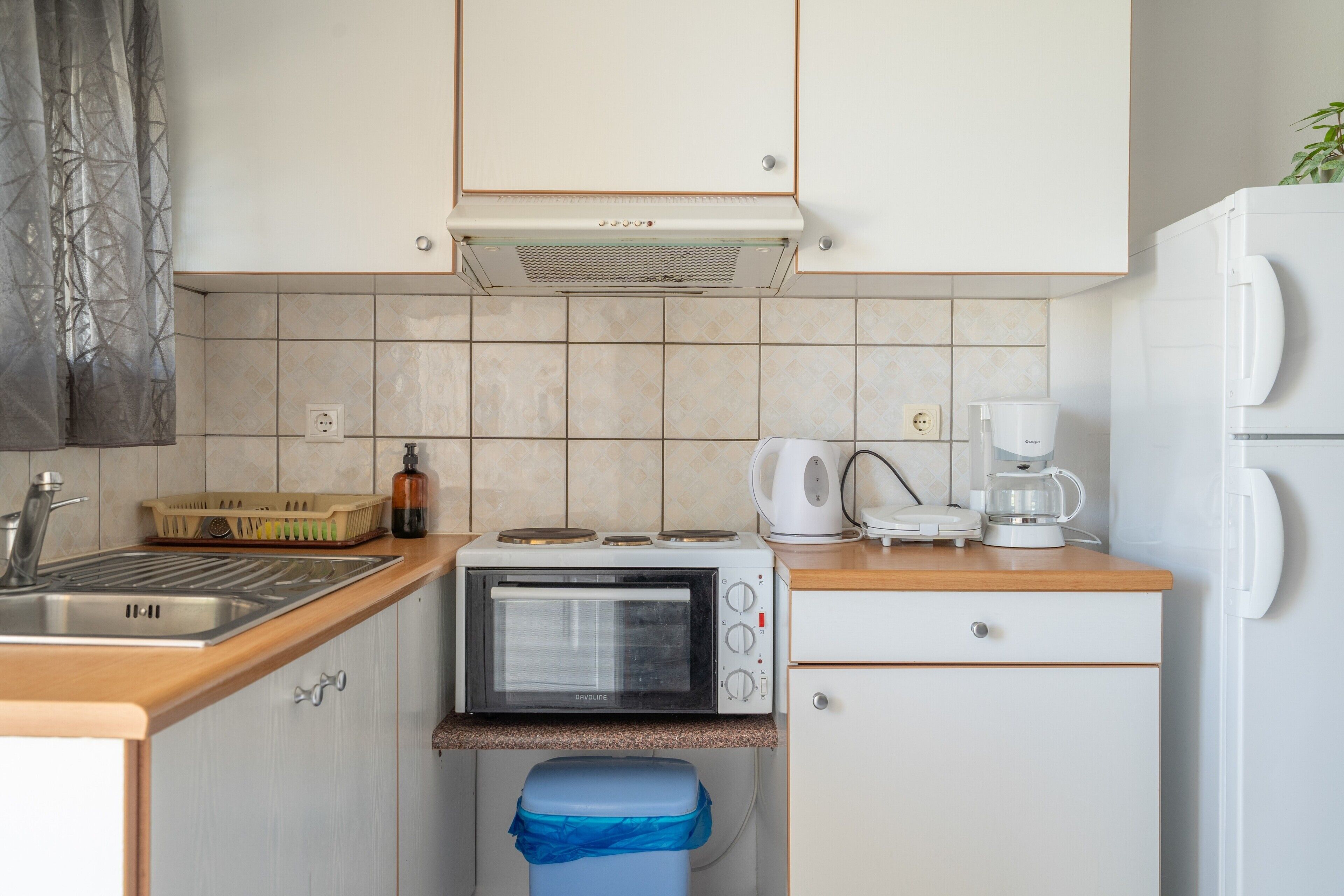 Een kleine keuken met een ingebouwde magnetron, koffiezetapparaat en broodrooster.