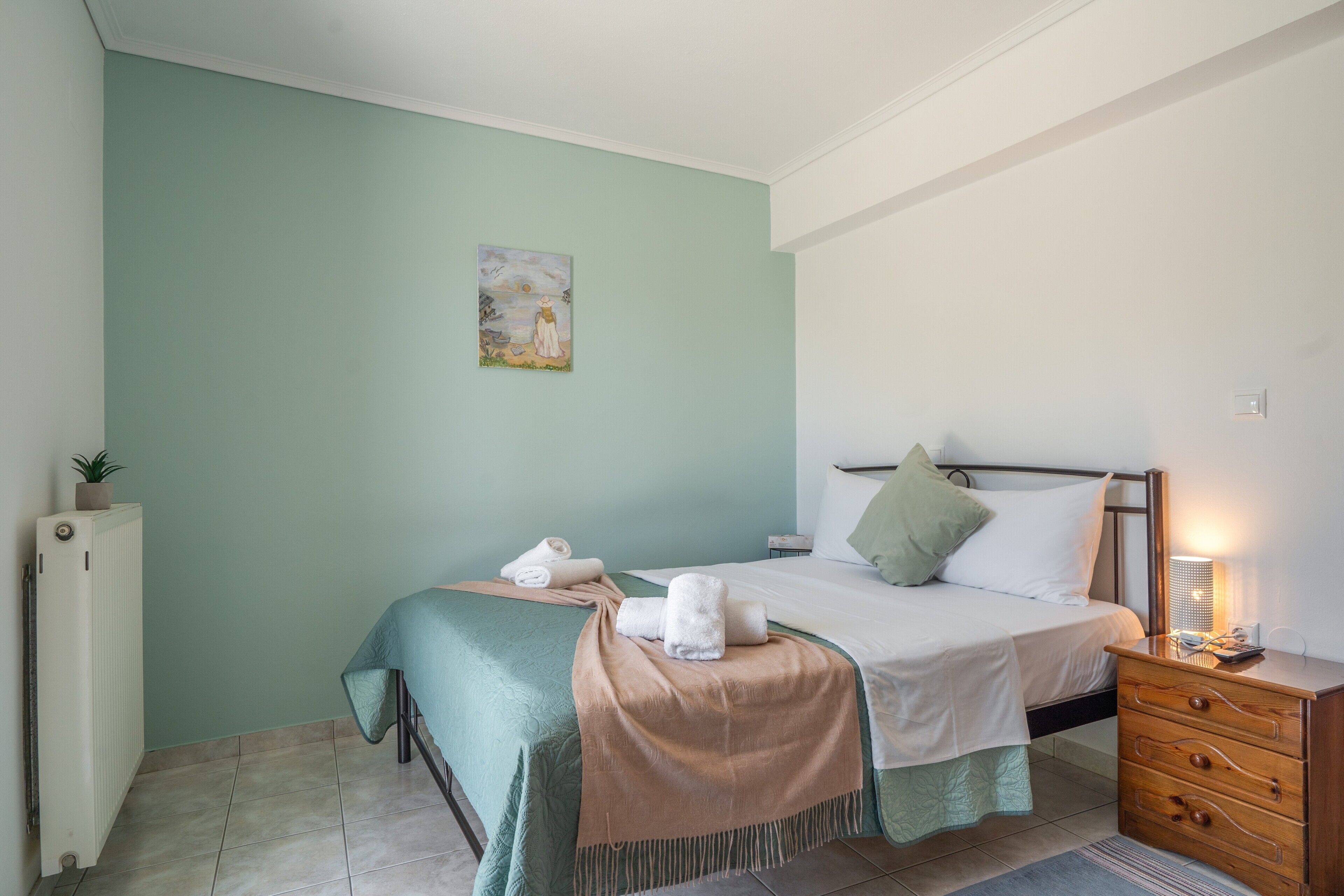 A bedroom with a bed, bedside table, and a radiator.