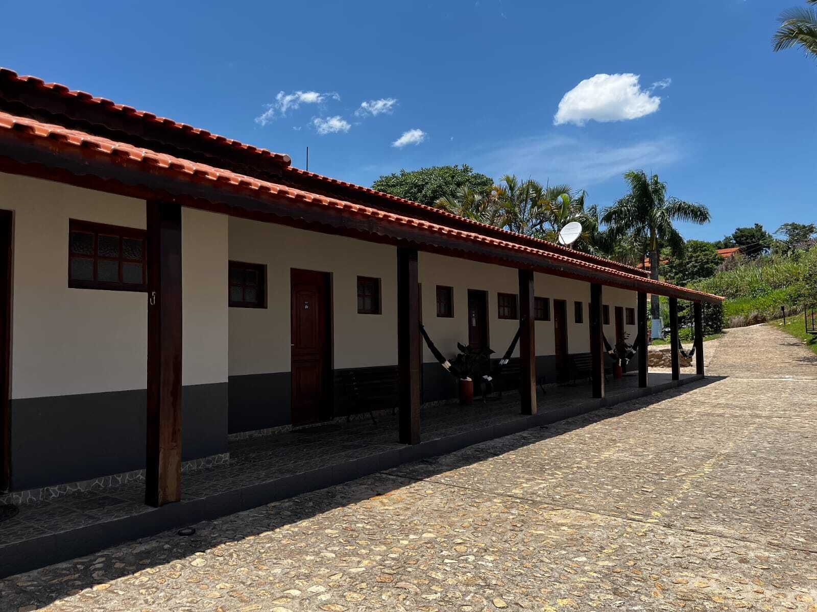 Um edifício com telhado de telhas, várias janelas e um caminho de pedras que o leva até ele.