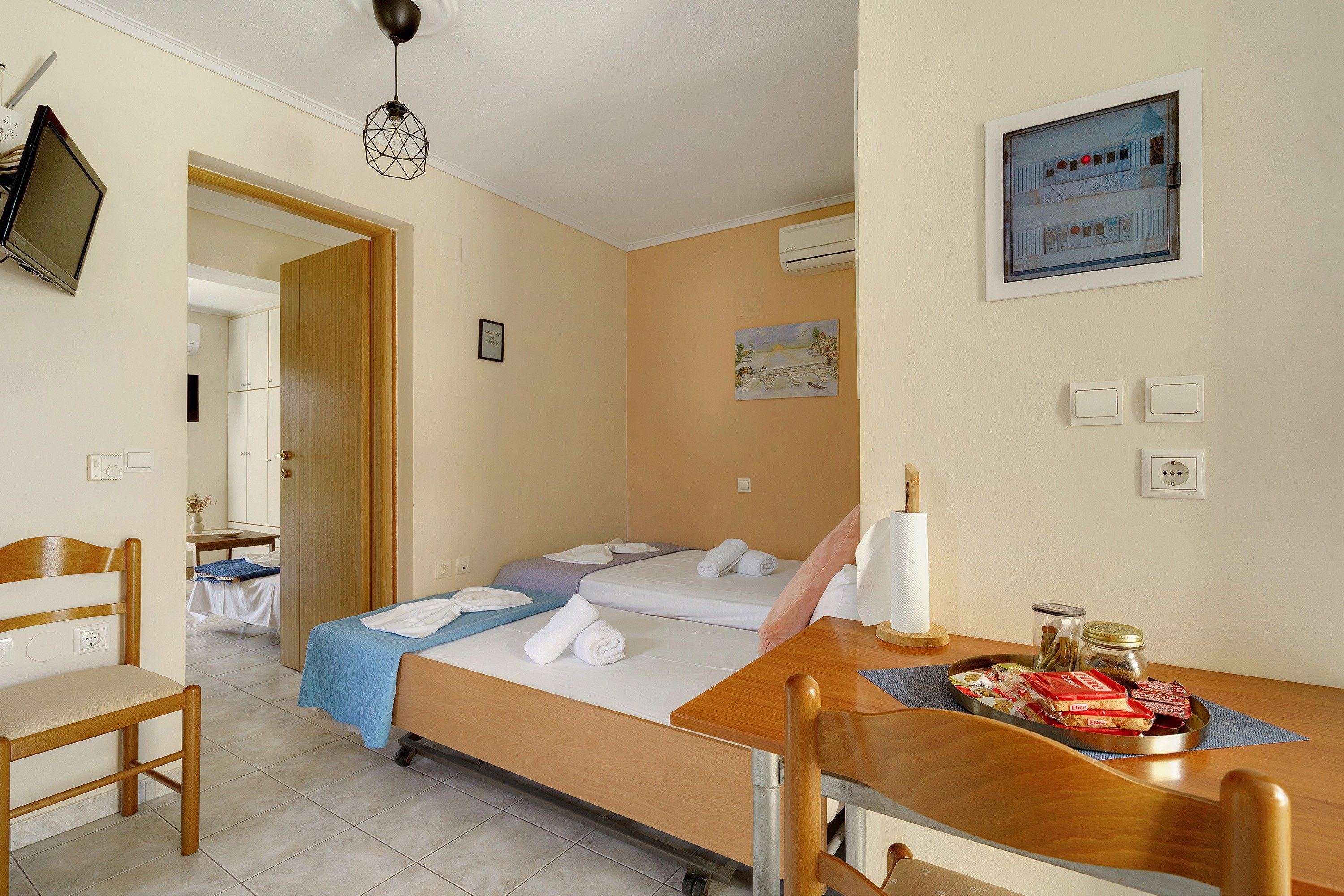 Ein Hotelzimmer mit einem Bett, einem Schreibtisch mit Stuhl, einem Esstisch mit Stuhl, einem Fernseher und einem Bild an der Wand.