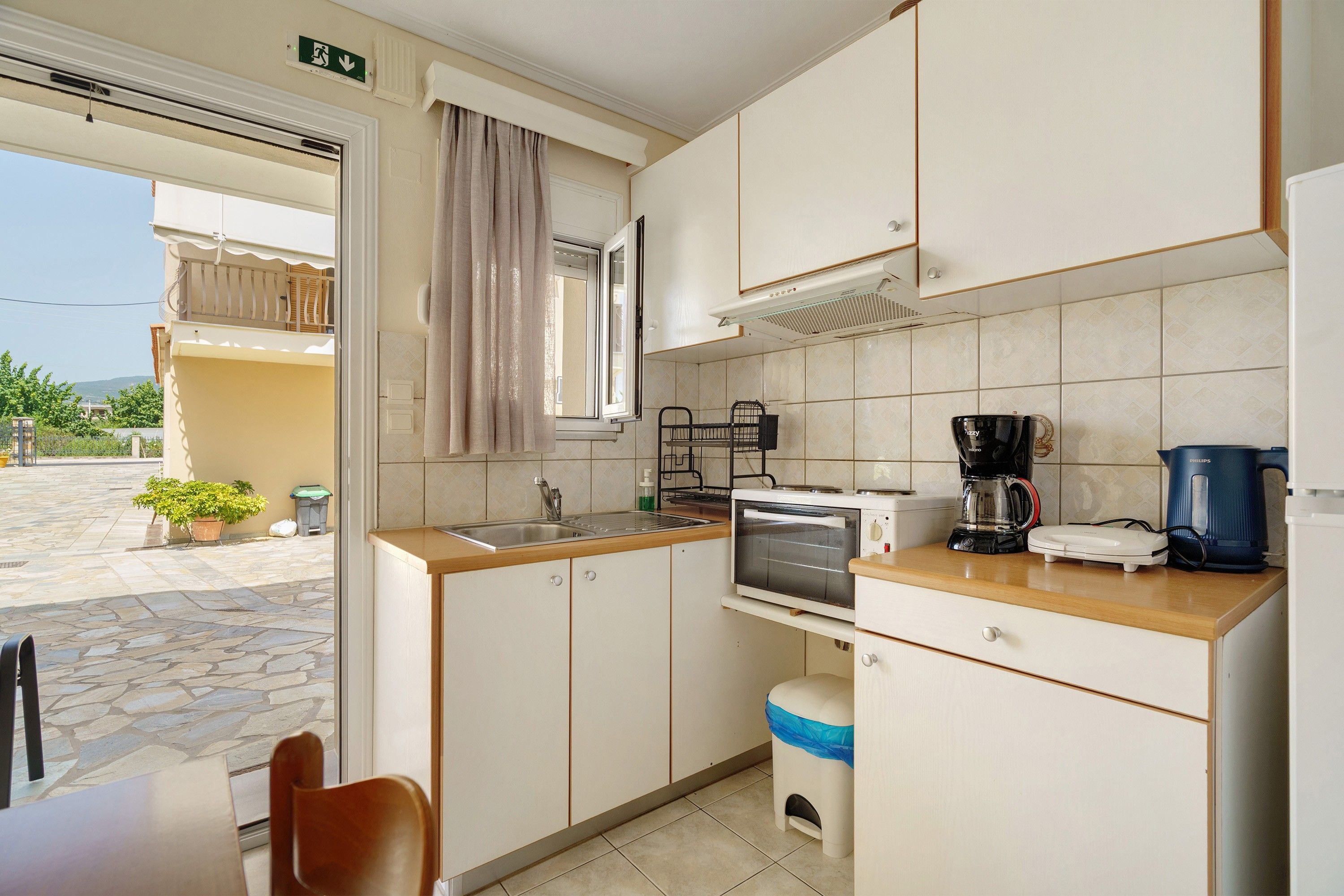 Cocina compacta con lavamanos, estufa, microondas y cafetera.