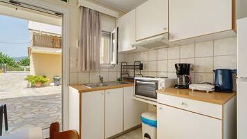 Cocina compacta con lavamanos, estufa, microondas y cafetera.