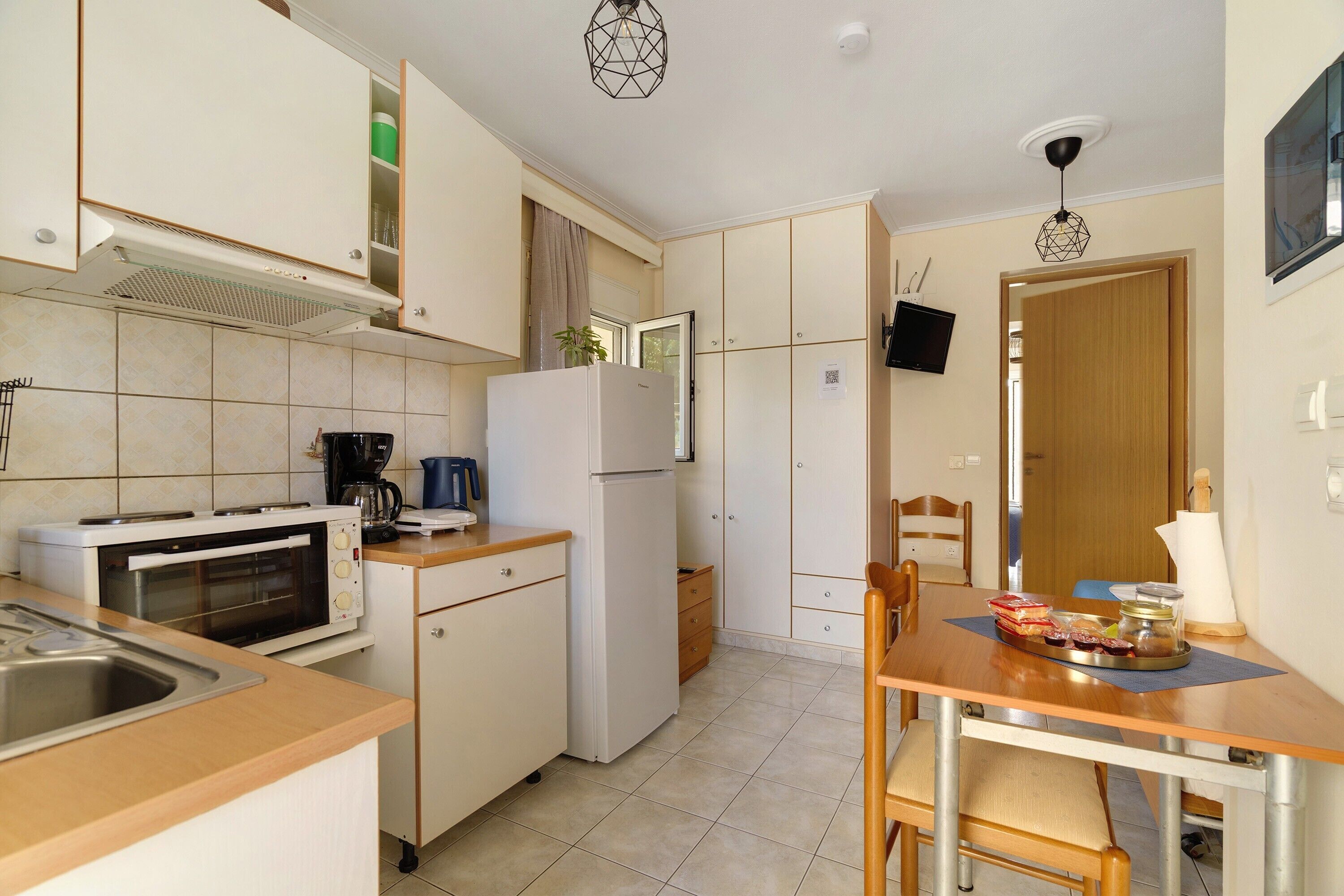 A compact kitchen with a built-in oven, a refrigerator, and a coffee maker.