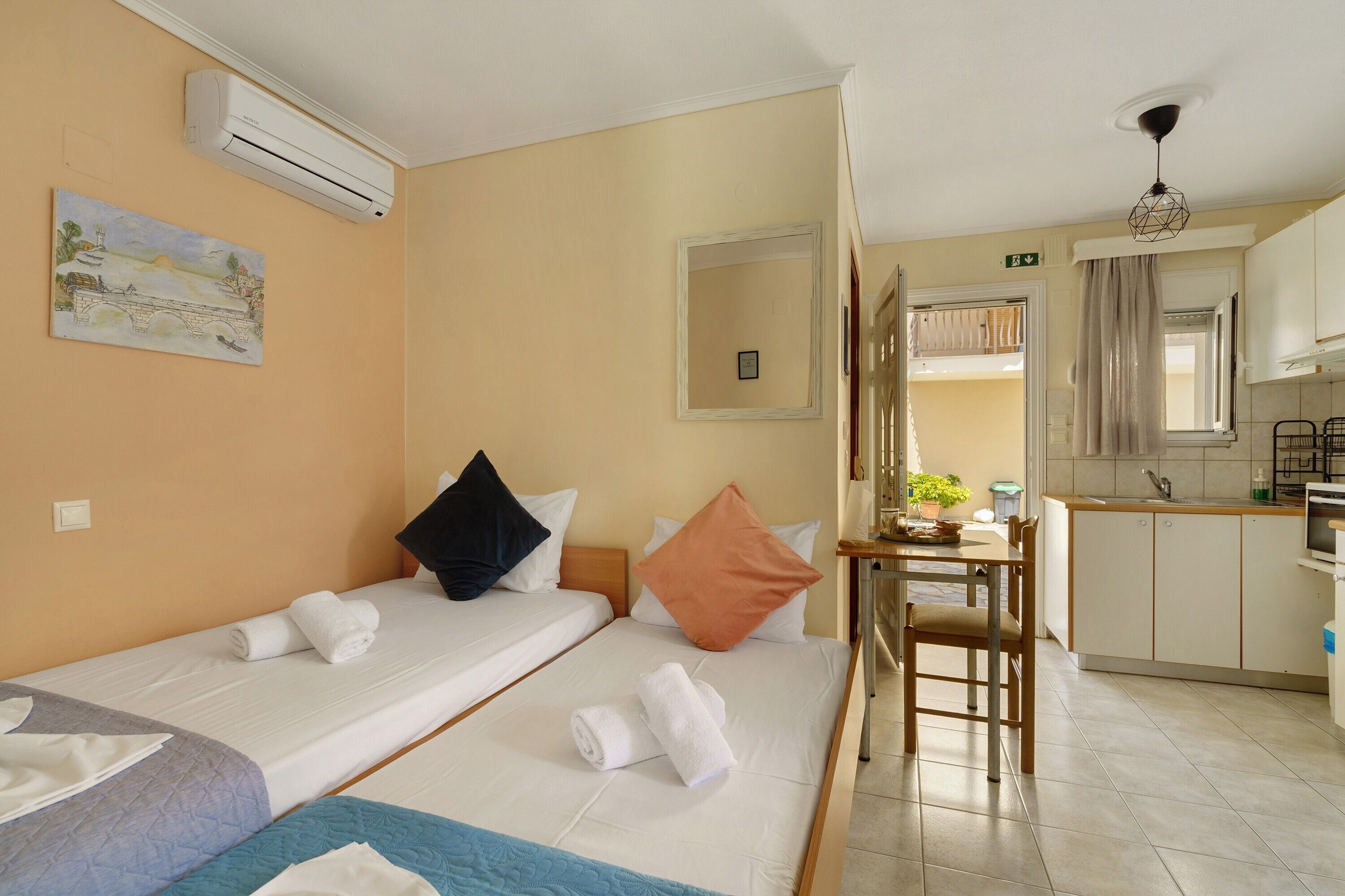 A hotel room with two beds, a kitchenette, and a small dining area.