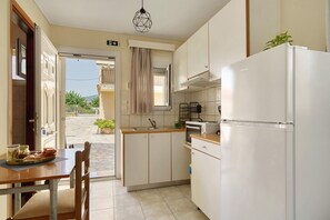 A compact kitchen with a dining area, a refrigerator, and a view of the outside.