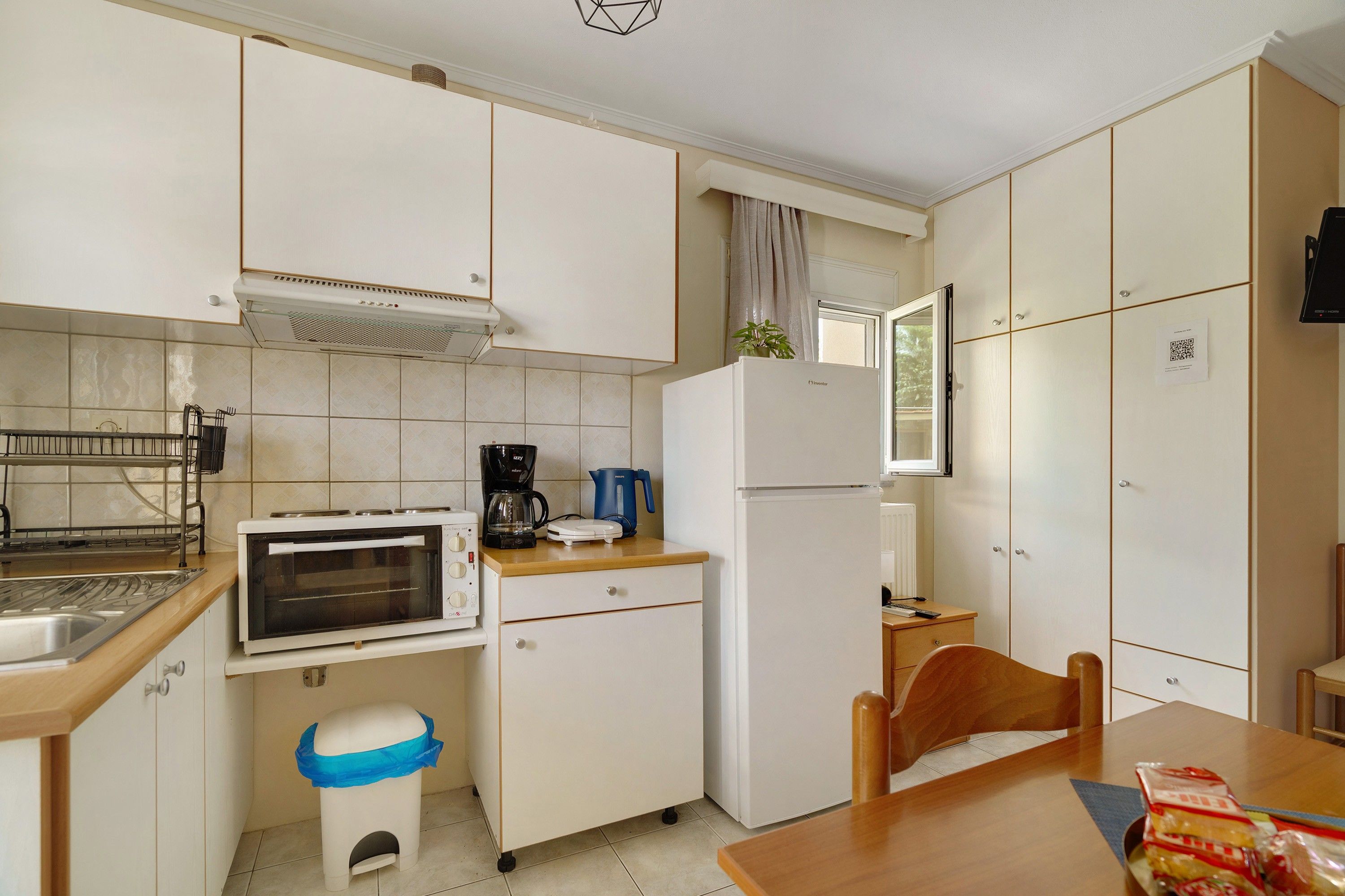 Una cocina compacta con horno integrado, cafetera y refrigerador.