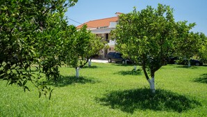A building with a red roof, surrounded by green grass and trees.