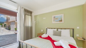A hotel room with a bed, a nightstand, a window, and a painting on the wall.