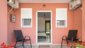 A hotel room entrance with two chairs, a bed, and a door leading inside.