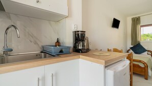 A compact kitchen with a sink, a coffee maker, and a refrigerator.