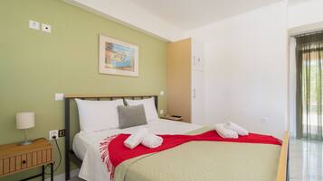 A hotel room with a bed, a nightstand, a lamp, a painting on the wall, and a window with curtains.