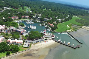 Vue aérienne d’une marina avec des bateaux, un quai et les bâtiments environnants.