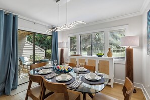 A dining area with a glass table, chairs, and a view of the outdoors. - Golf View Villa Near Harbour Town Marina! (Hilton Head Island)