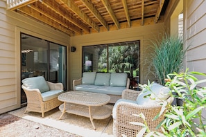 A covered patio area with wicker furniture, including a sofa and chairs, and a small table. - Golf View Villa Near Harbour Town Marina! (Hilton Head Island)