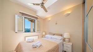 Una camera da letto con un letto, due comodini con lampade, una ventola a soffitto, una finestra con persiane e una decorazione a forma di stella sul muro.