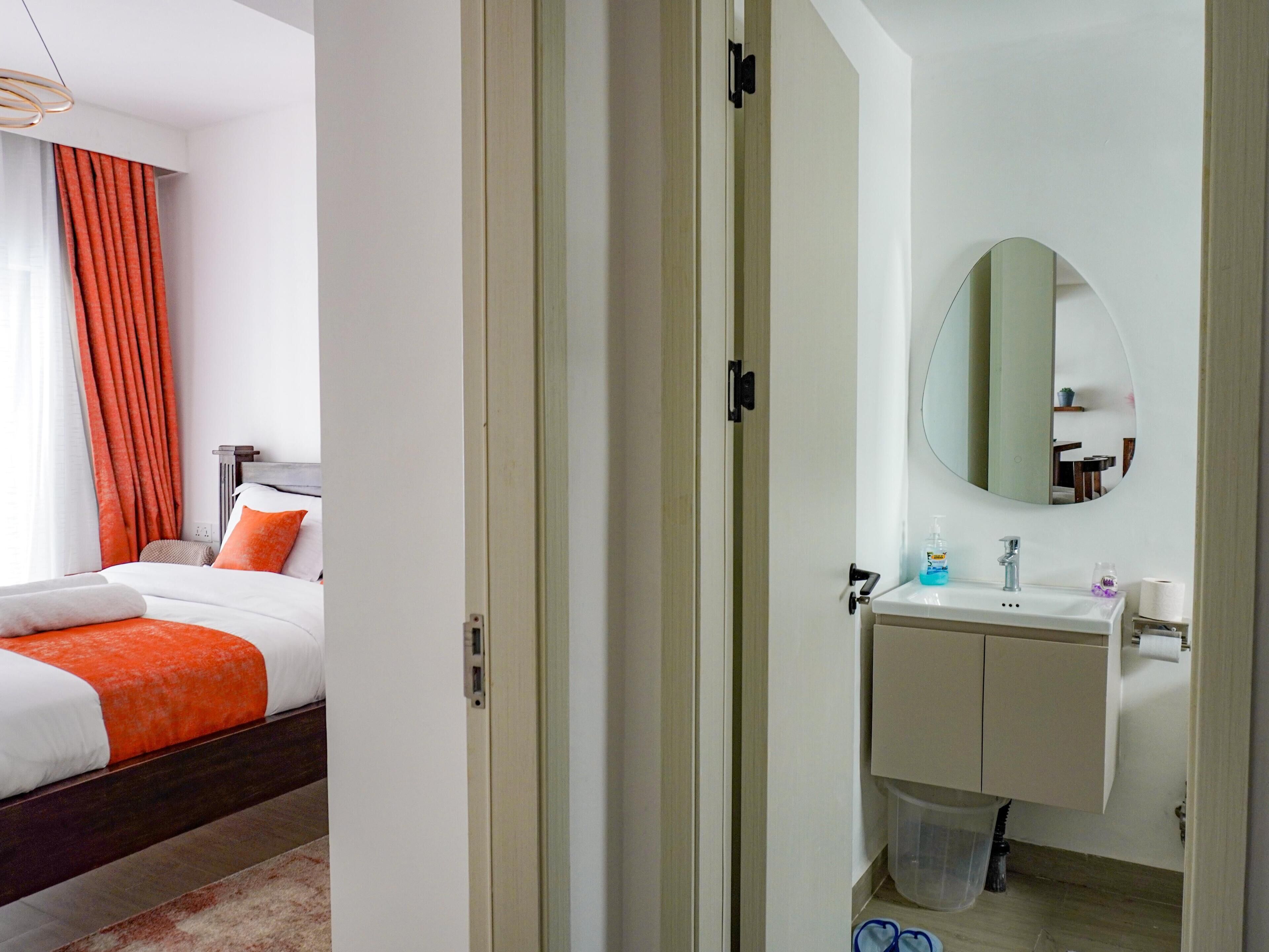 Camera d'albergo con un letto, bagno con lavandino e specchio, e vista esterna.