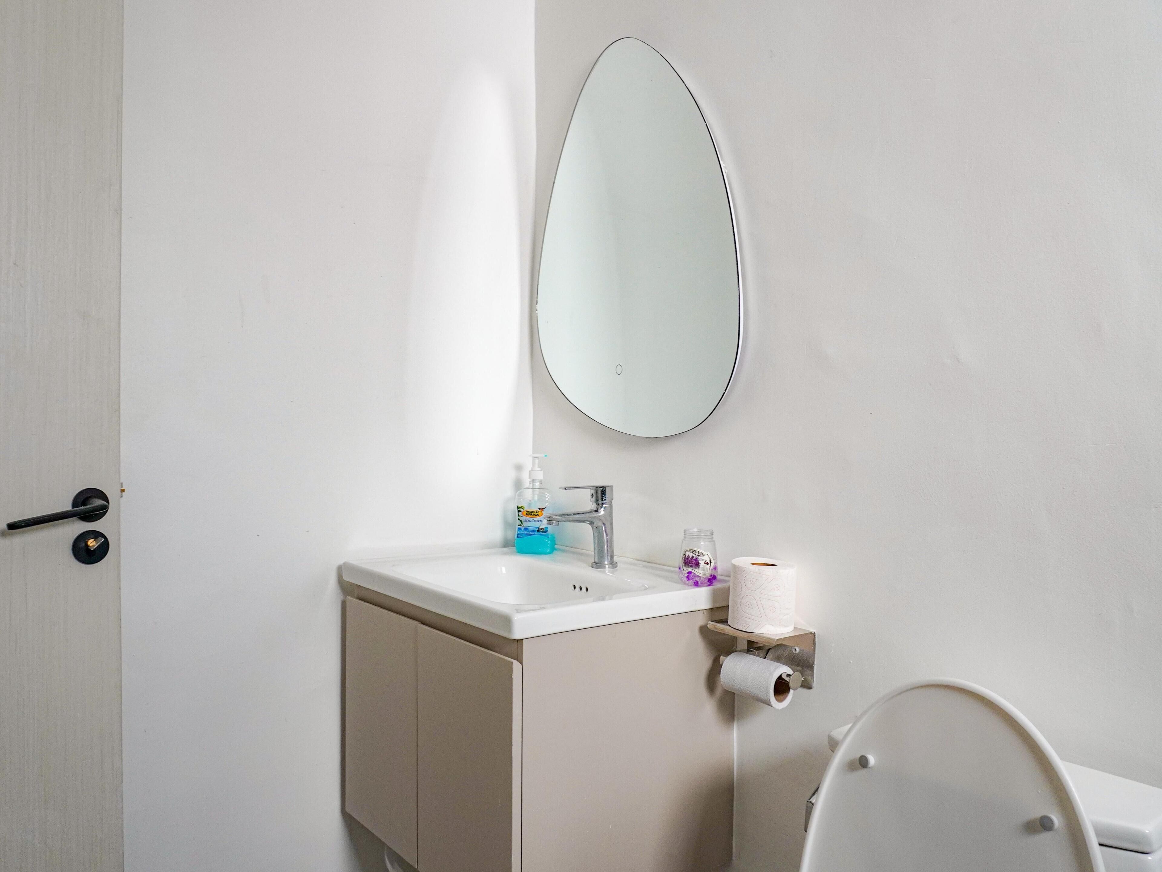 Un baño con lavamanos, espejo, inodoro y una puerta.