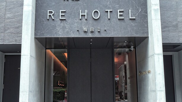 L’entrée d’un hôtel au design moderne, avec une enseigne bien visible portant le nom de l’établissement.