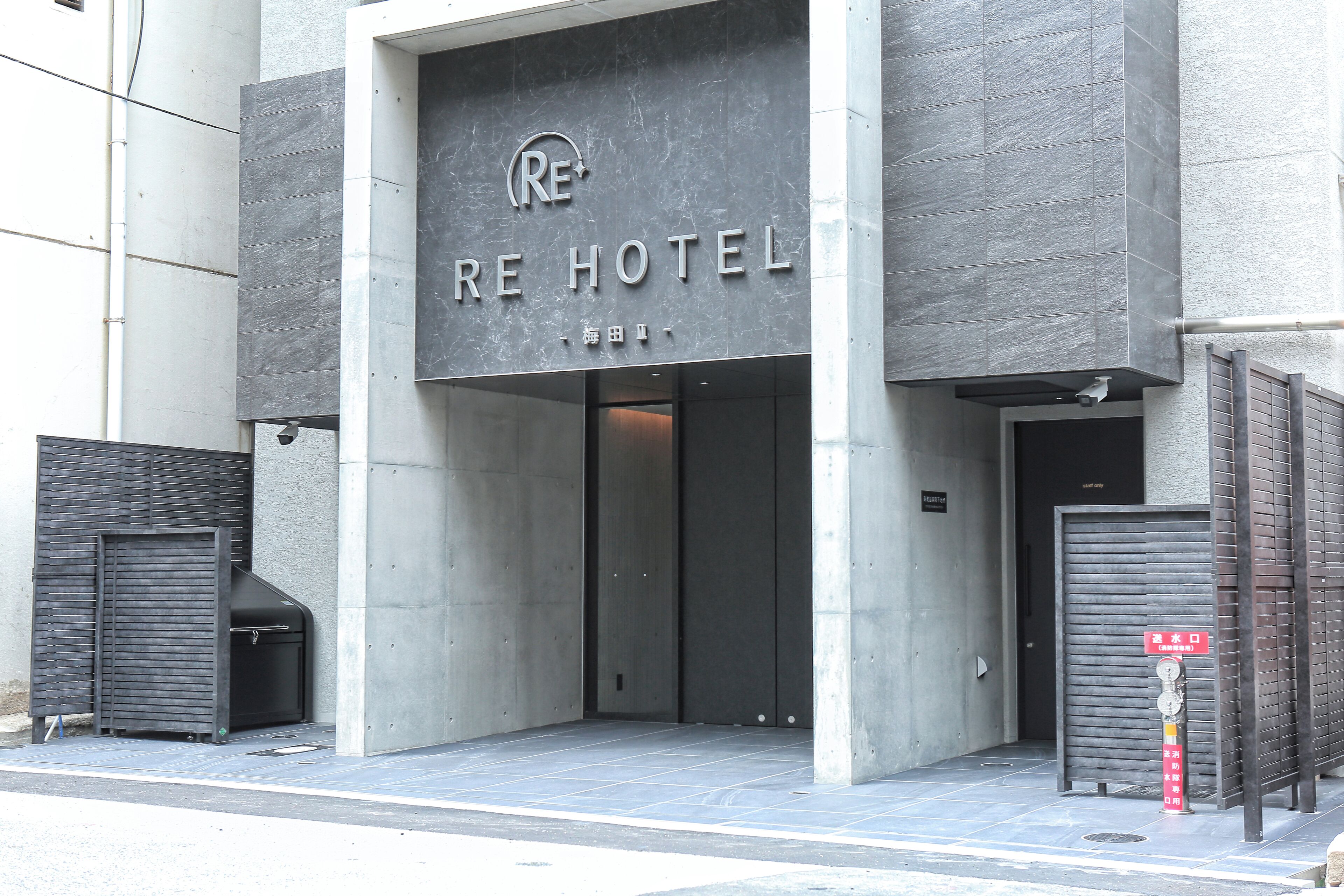 A hotel entrance with a modern design, featuring a large sign with the hotel's name and a visible entrance door.