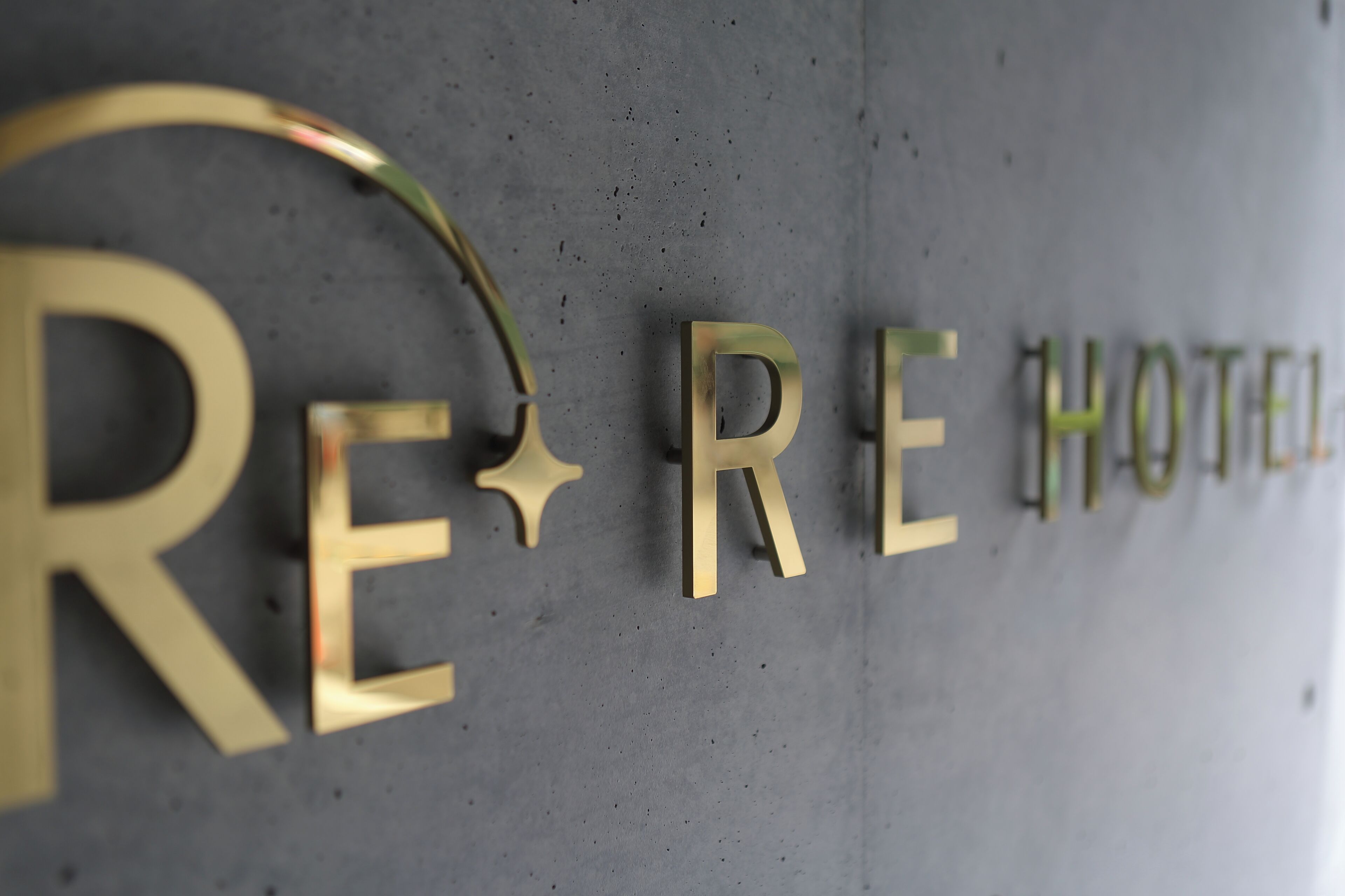 Een muur met de tekst 'RE HOTEL' in grote, gouden letters.