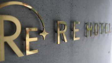Een muur met de tekst 'RE HOTEL' in grote, gouden letters.