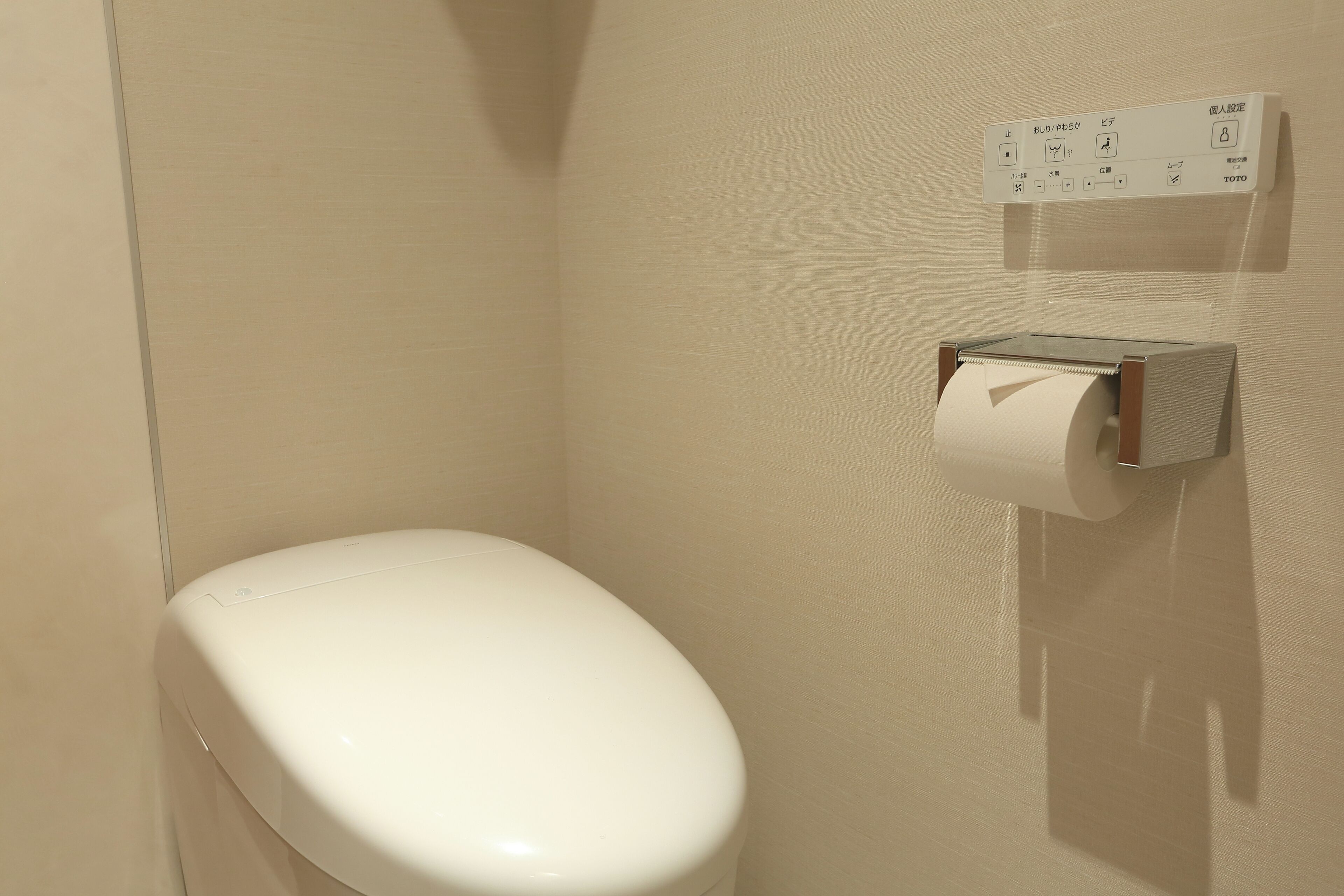 Des toilettes équipées d’un distributeur de serviettes en papier fixé au mur.