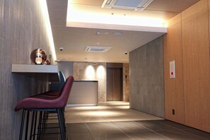 Un intérieur moderne comprenant un bar, un comptoir d’accueil et un ascenseur.