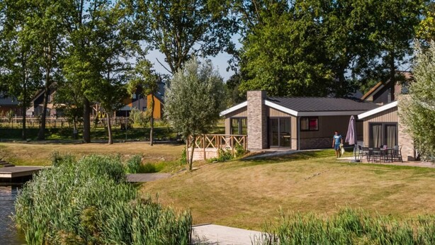 A modern building with a stone facade, large windows, and a patio area with outdoor furniture. - Holiday Home in Kampen With Terrace (Kampen)