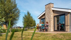 A modern building with a brick facade and large glass doors, surrounded by a grassy area and trees. - Holiday Home in Kampen With Terrace (Kampen)