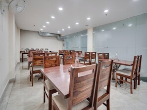 A conference room with wooden tables and chairs, recessed ceiling lights, and a glass partition wall. - Townhouse Sector 63 A Noida (Noida)