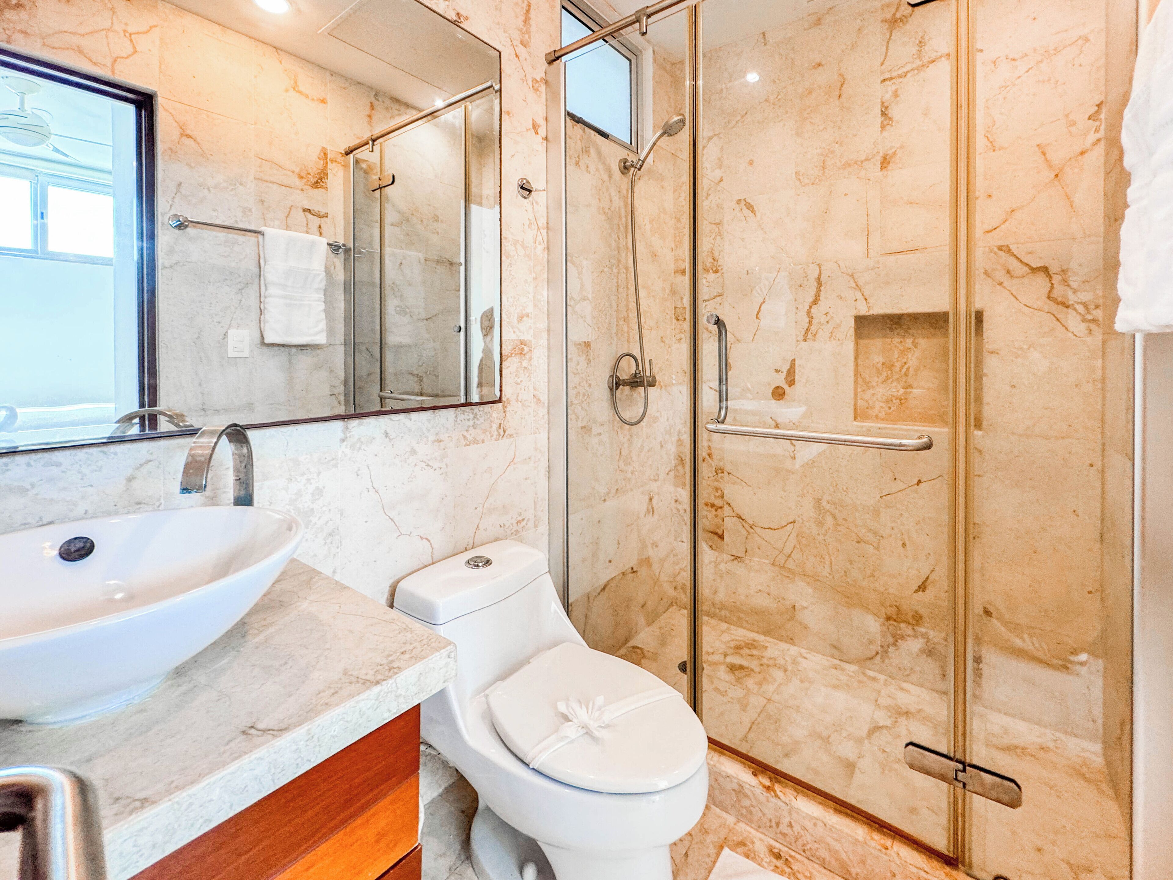 Une salle de bain moderne avec un lavabo, des toilettes et une douche à parois de verre.