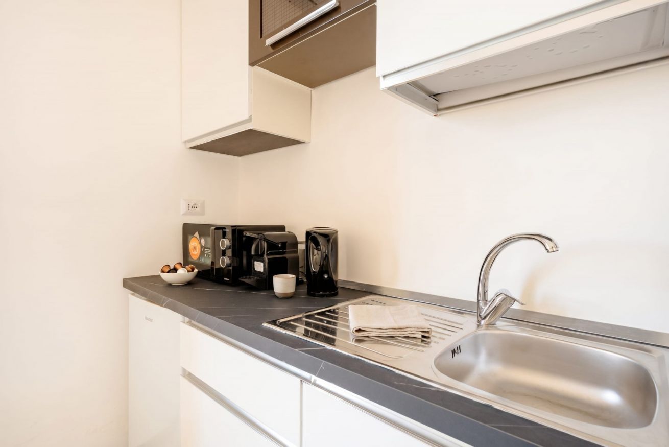 Eine moderne Küche mit Spüle aus Edelstahl, Kaffeemaschine und Wasserkocher.