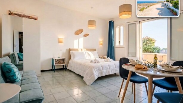 Une chambre d’hôtel comprenant un lit, une table à manger avec des chaises, un canapé, une table de chevet et une fenêtre donnant sur la plage.