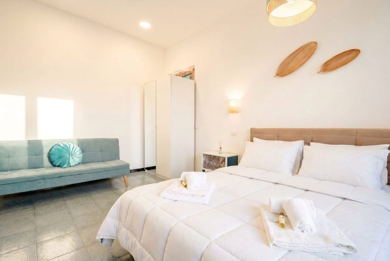 Une chambre d’hôtel comprenant un lit, un canapé, une table de chevet et un luminaire fixé au mur.