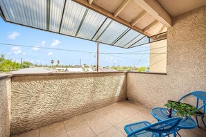 A covered outdoor area with a view of the surrounding neighborhood, including palm trees and buildings.