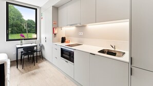 Una cucina moderna con mobili bianchi, forno integrato, lavello e finestra con vista sul verde.