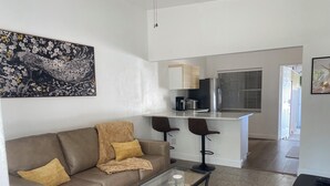 A modern living room with a brown leather sofa, a glass coffee table, and a patterned rug. - The Peacock Pad Retro-Vibe, Newly Renovated 2 bed Duplex, Hourglass-Sodo area (Orlando)