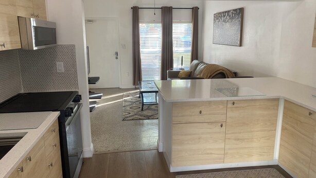 A modern kitchen with a microwave, stove, and wooden cabinets. - The Peacock Pad Retro-Vibe, Newly Renovated 2 bed Duplex, Hourglass-Sodo area (Orlando)