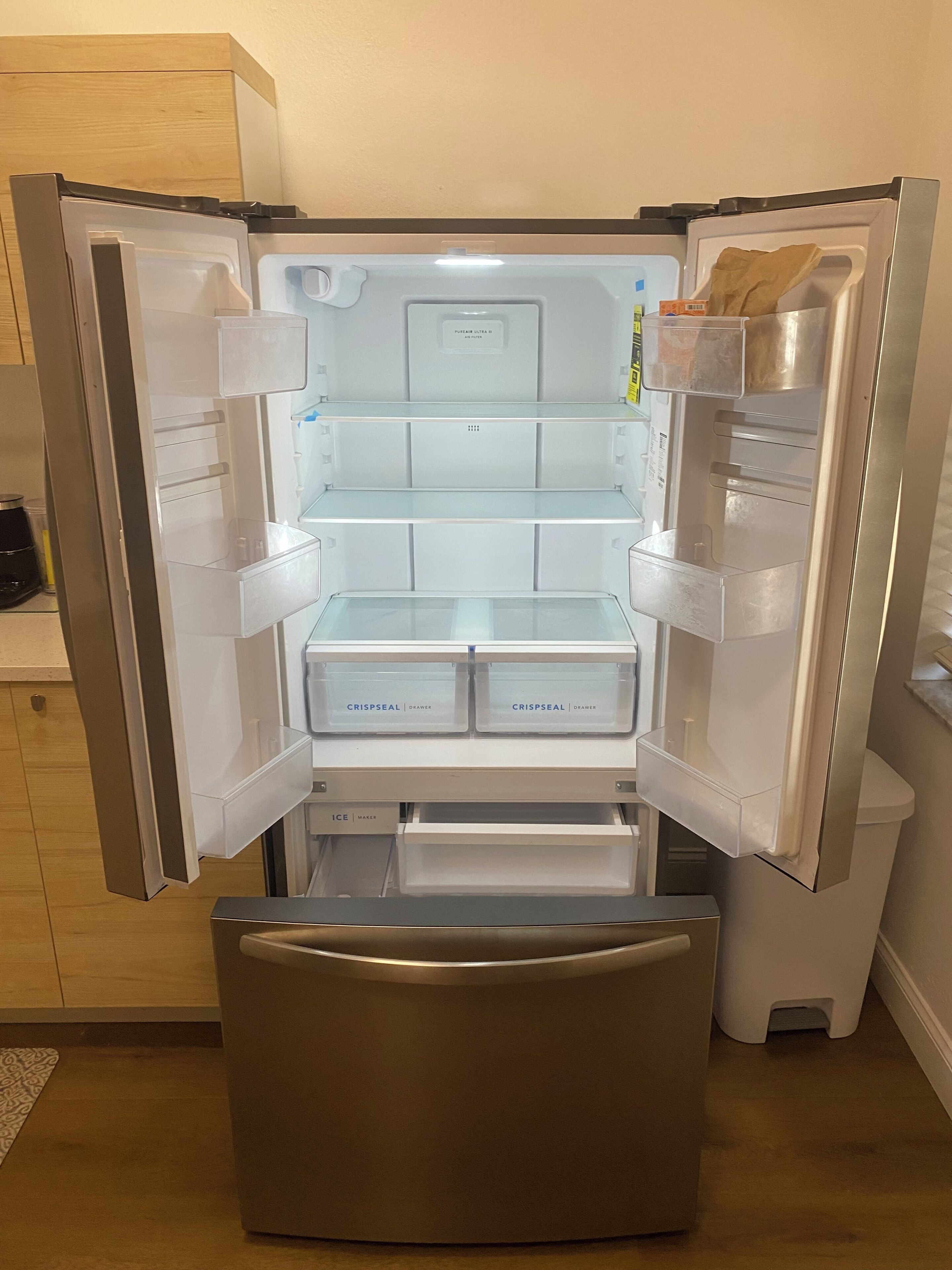 An open refrigerator with labeled drawers for 'CRISPEAL DRAWER' and 'ICE MAKER.'
